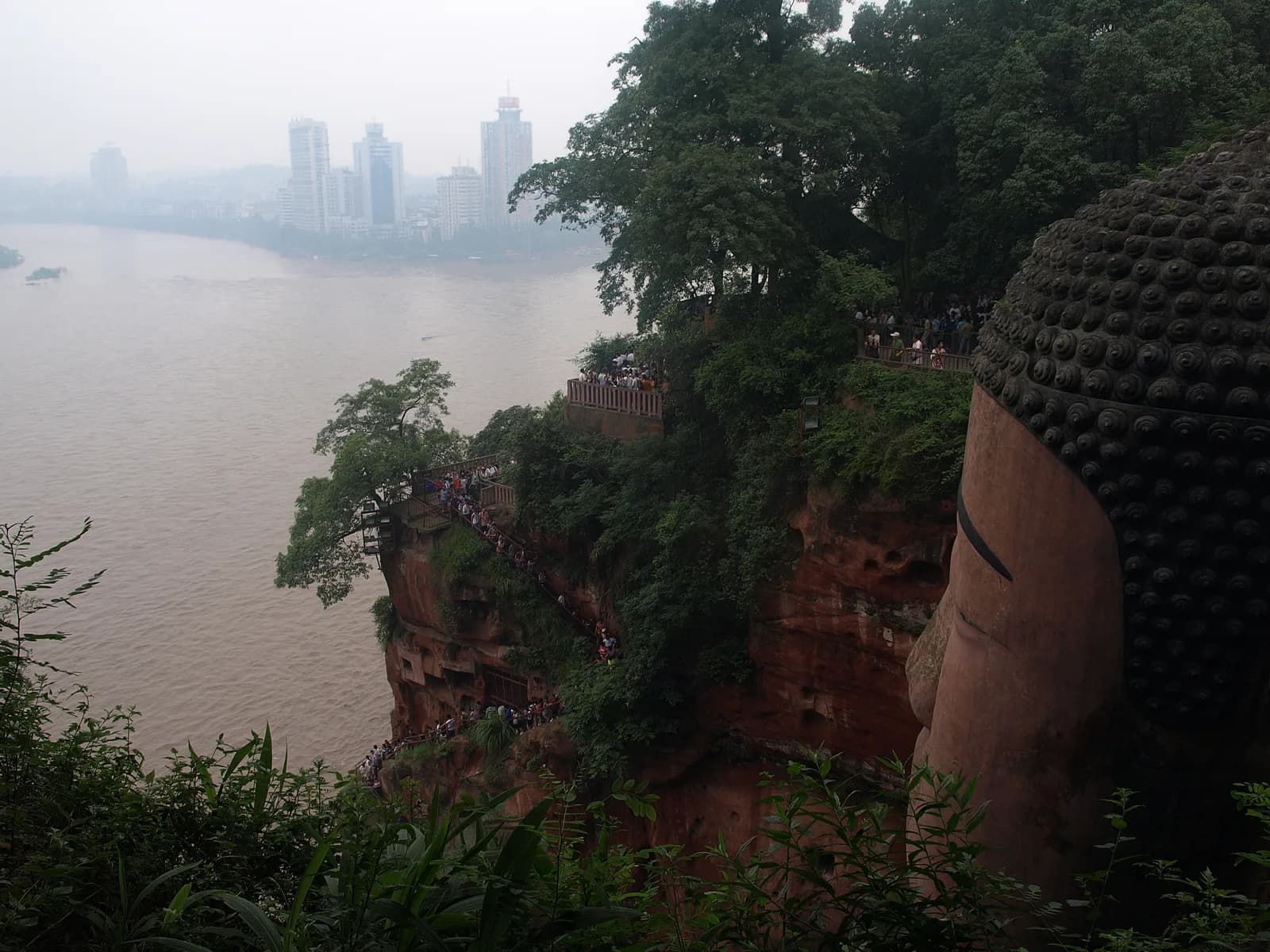 The full seated figure of the Leshan Giant Buddha seen from the Min River, the view passengers get from the sightseeing cruise