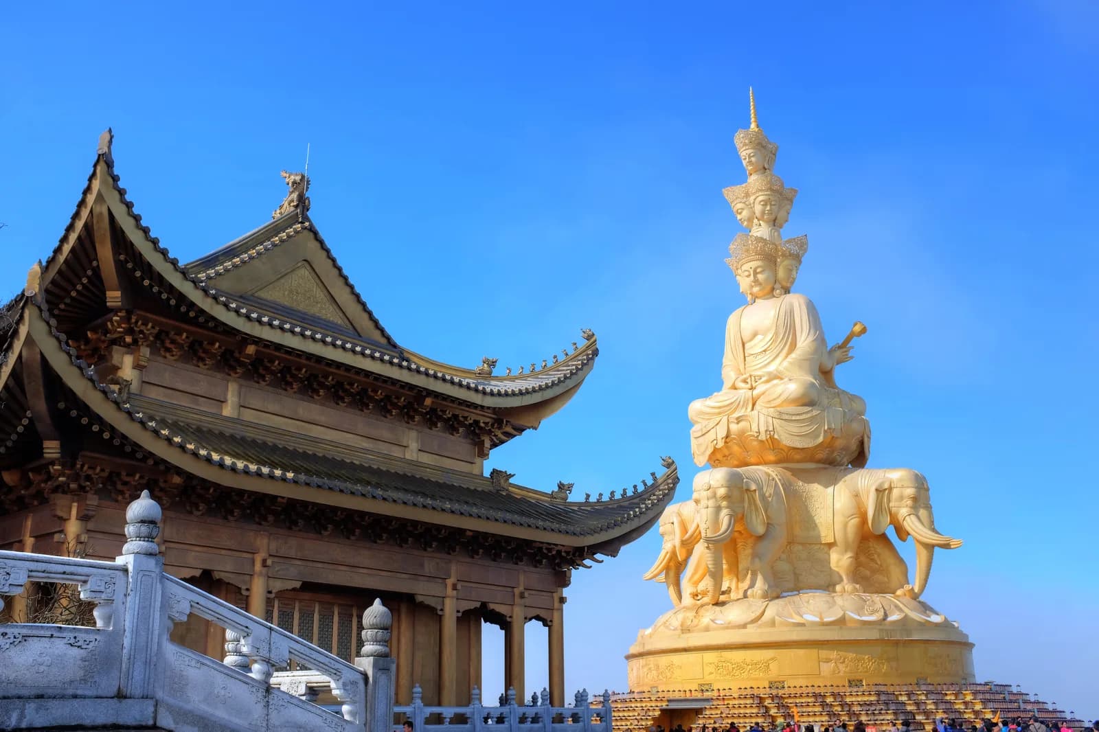 The golden multi-faced Puxian statue and temple roofs above a sea of clouds at the Golden Summit of Mount Emei