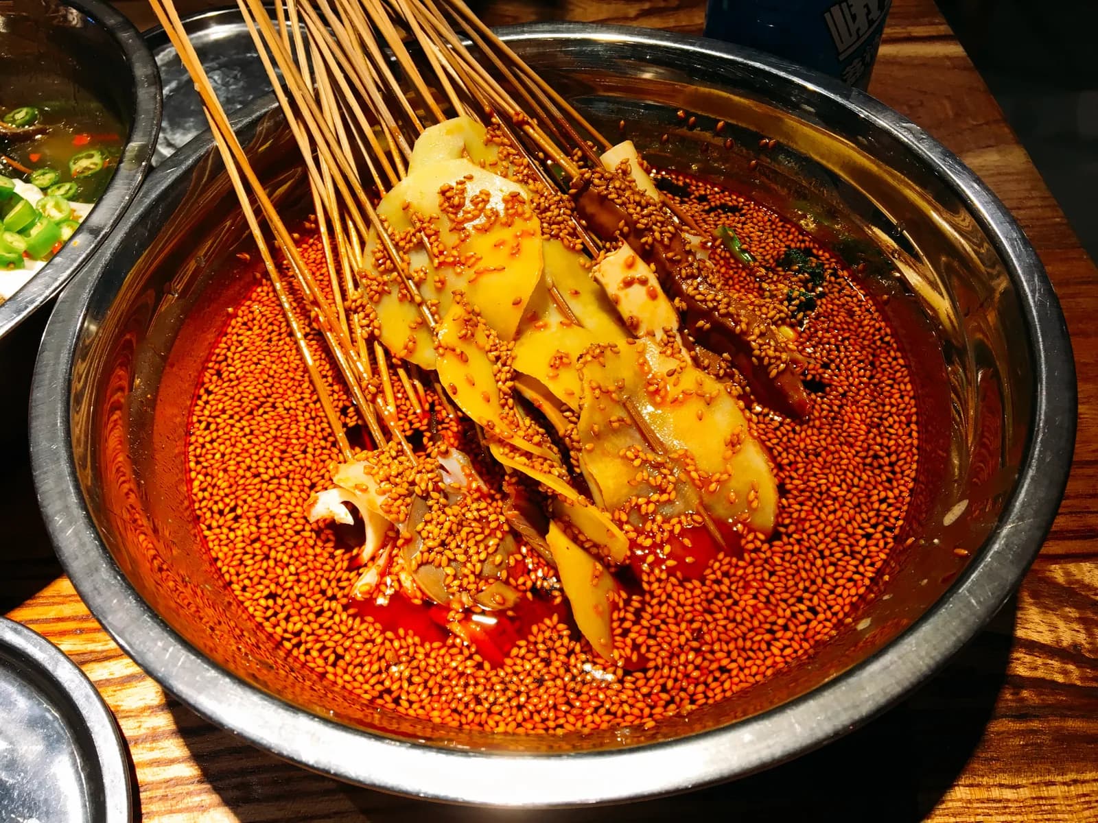 Skewers of chicken and vegetables steeping in a pot of red chili oil, the Leshan dish known as bobo chicken