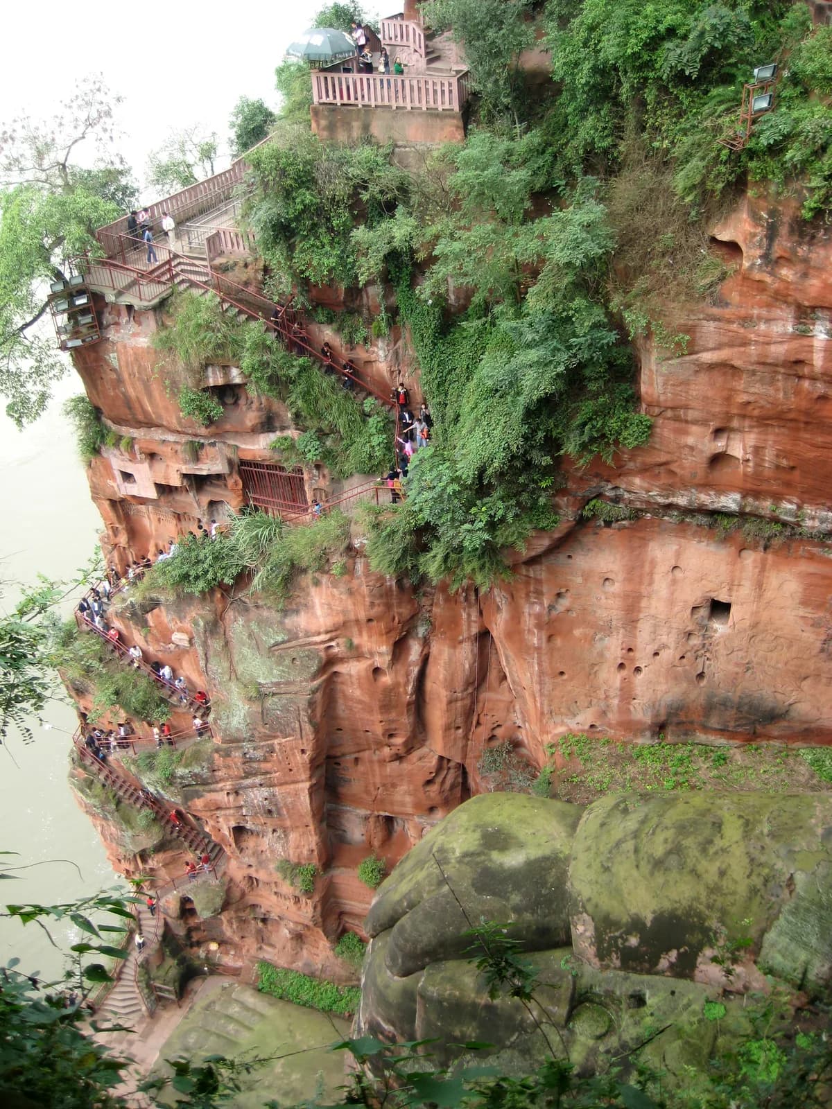 Visitors descending the narrow cliff-cut staircase beside the Leshan Giant Buddha toward its feet