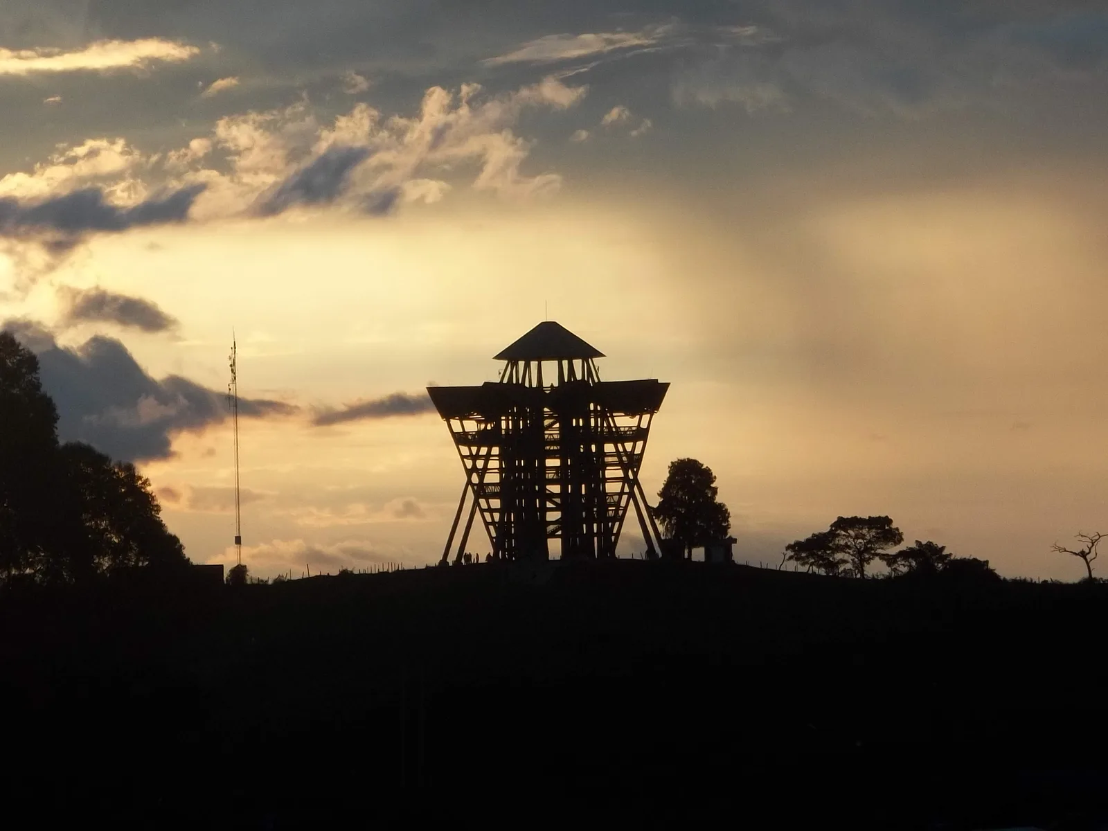 Silhouette of the wooden Mirador Colina Iluminada tower on a hilltop at sunset in Filandia, Colombia