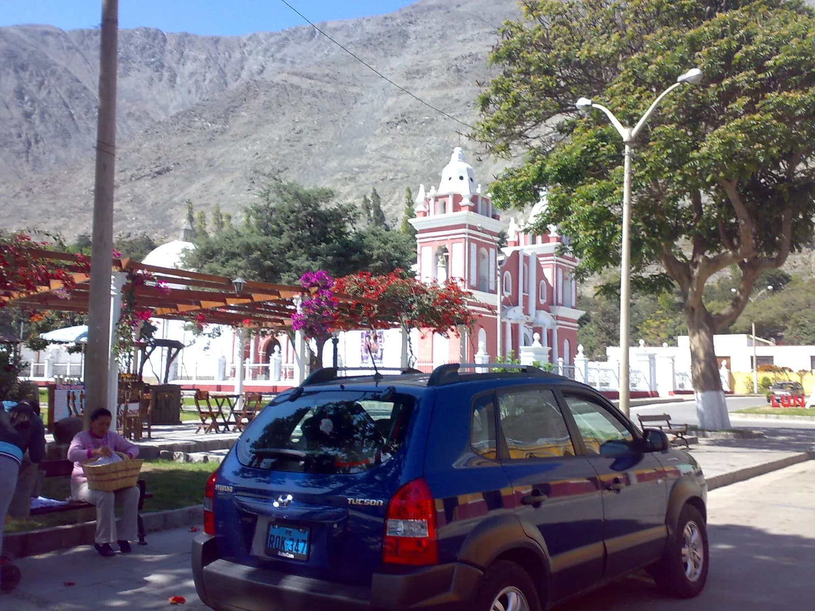 The Plaza de Armas of Lunahuaná with trimmed gardens, palms and the colonial church behind