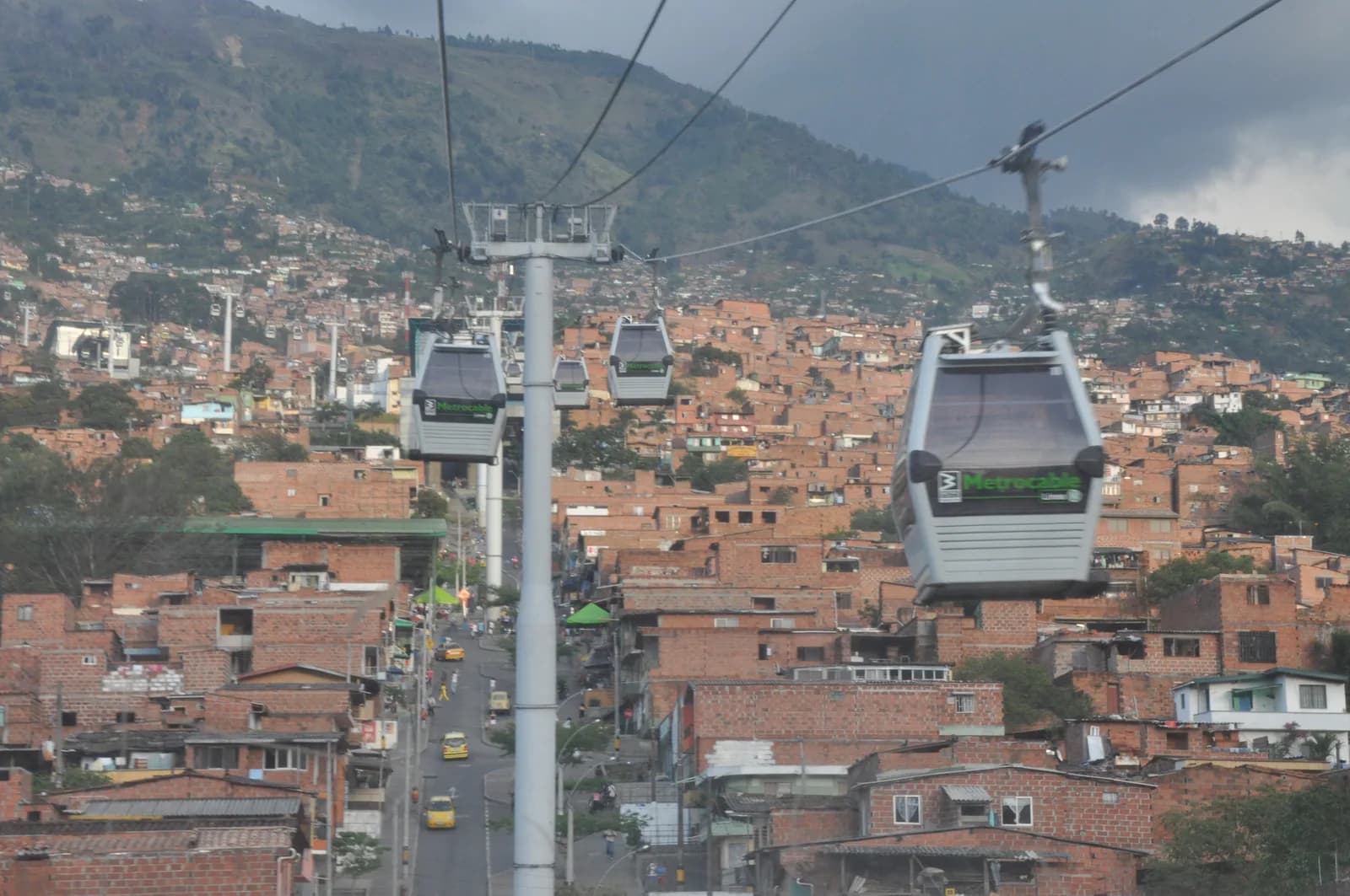 Metrocable gondolas rising over the brick rooftops of Medellín's hillside barrios toward the valley rim