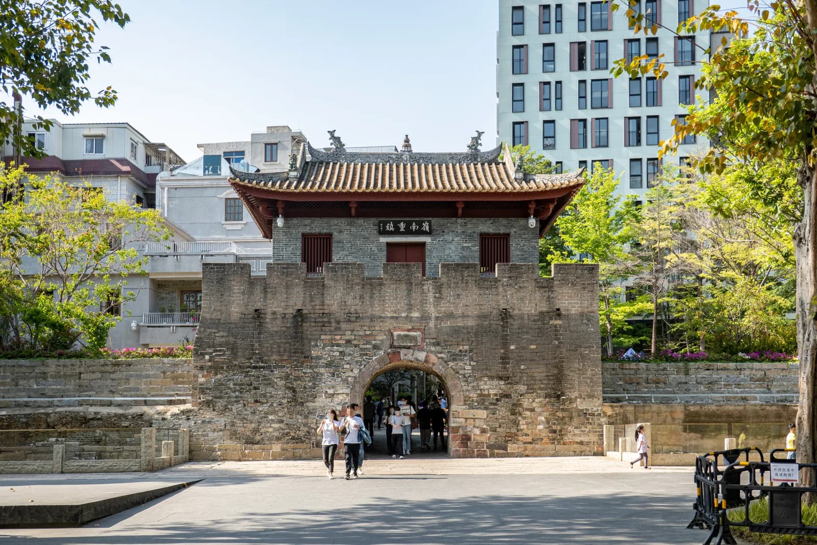 The restored south gate of Nantou Ancient City in Shenzhen with visitors walking through the stone archway