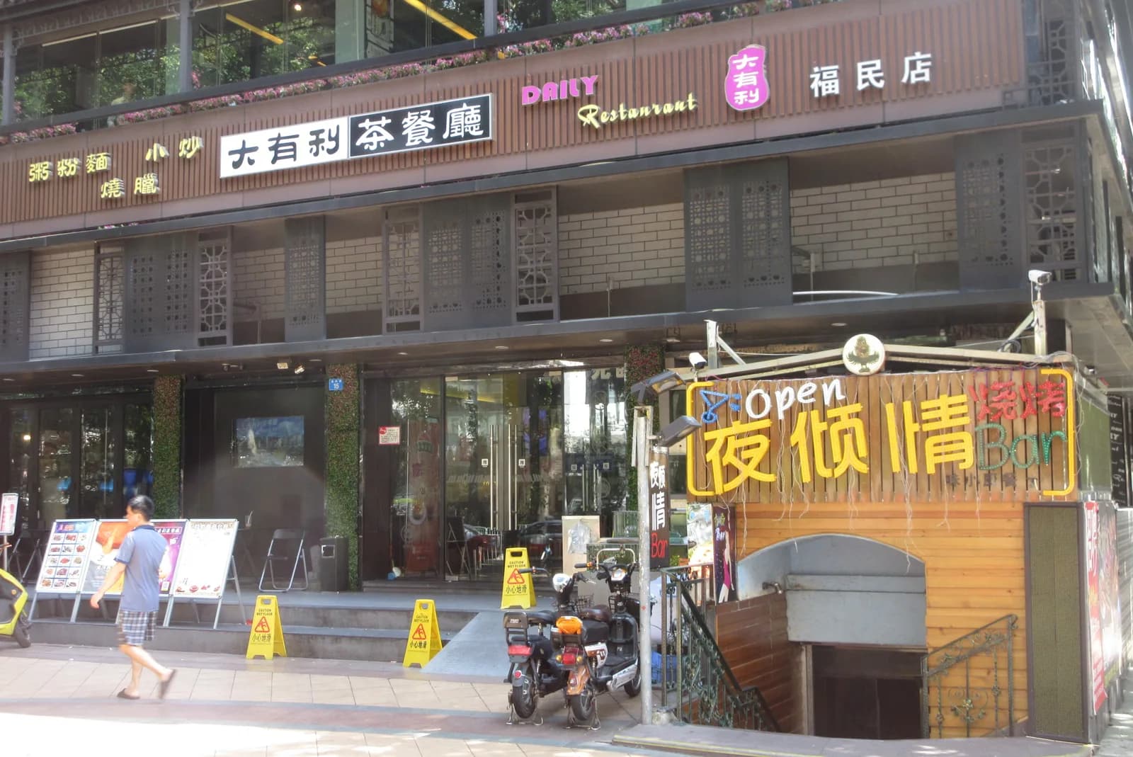 Small restaurants with Chinese signage lining a narrow street in Shuiwei Cun urban village on Fumin Road, Futian, Shenzhen