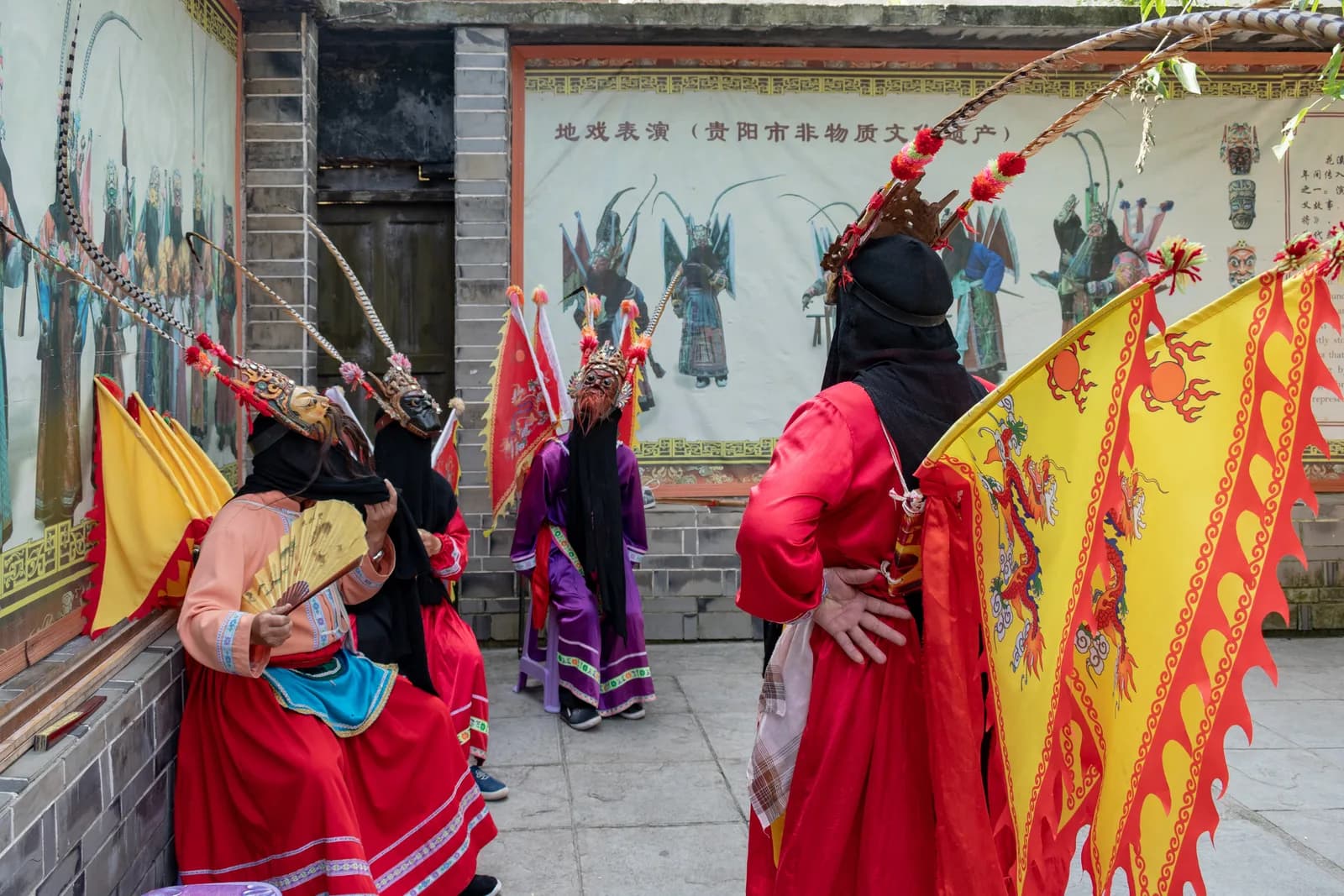 Masked ground opera performers in embroidered costumes on a stage in Qingyan Ancient Town, Guiyang