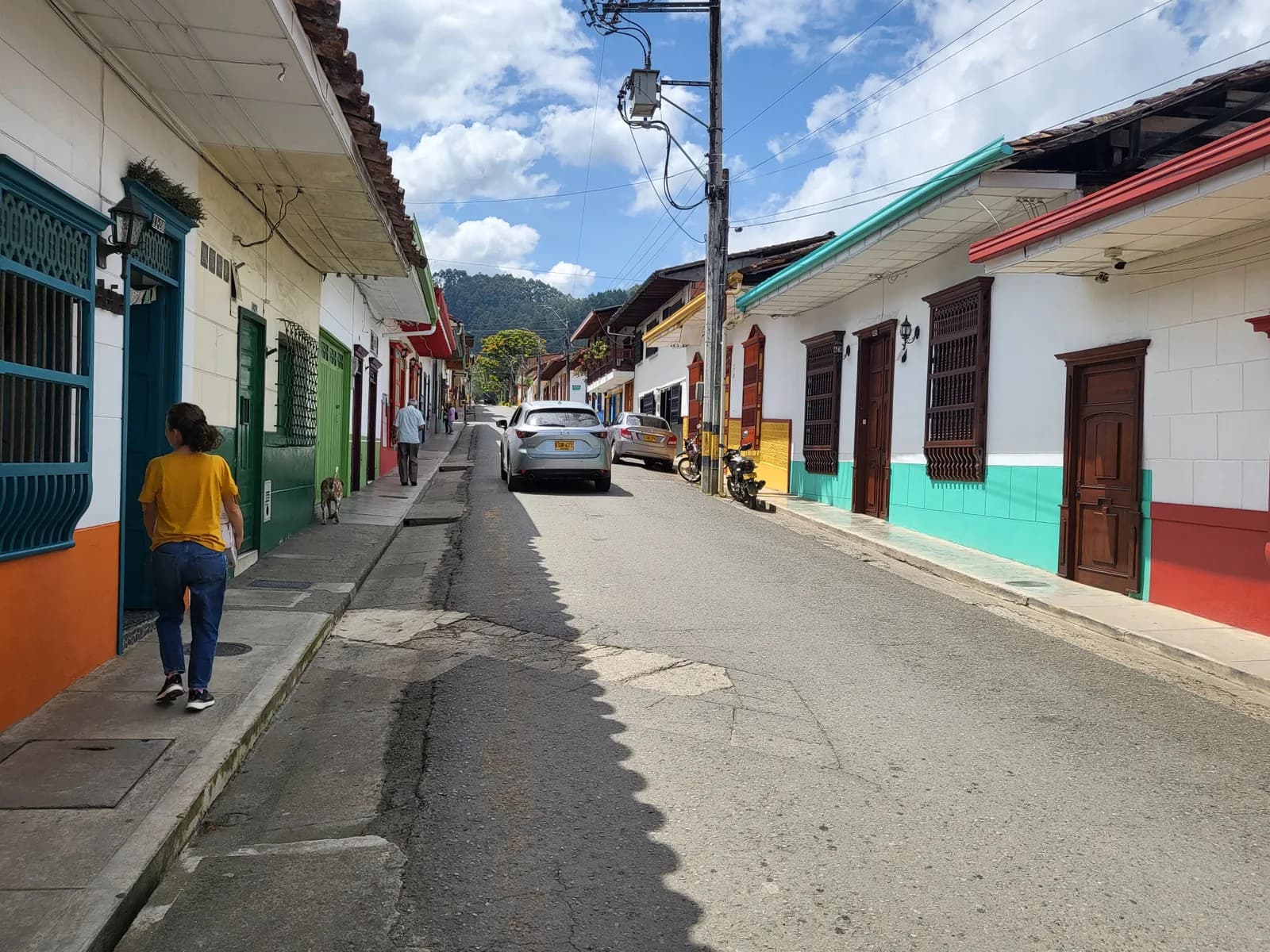 A cobbled street of whitewashed houses with brightly painted doors and balconies in Jardín, Antioquia