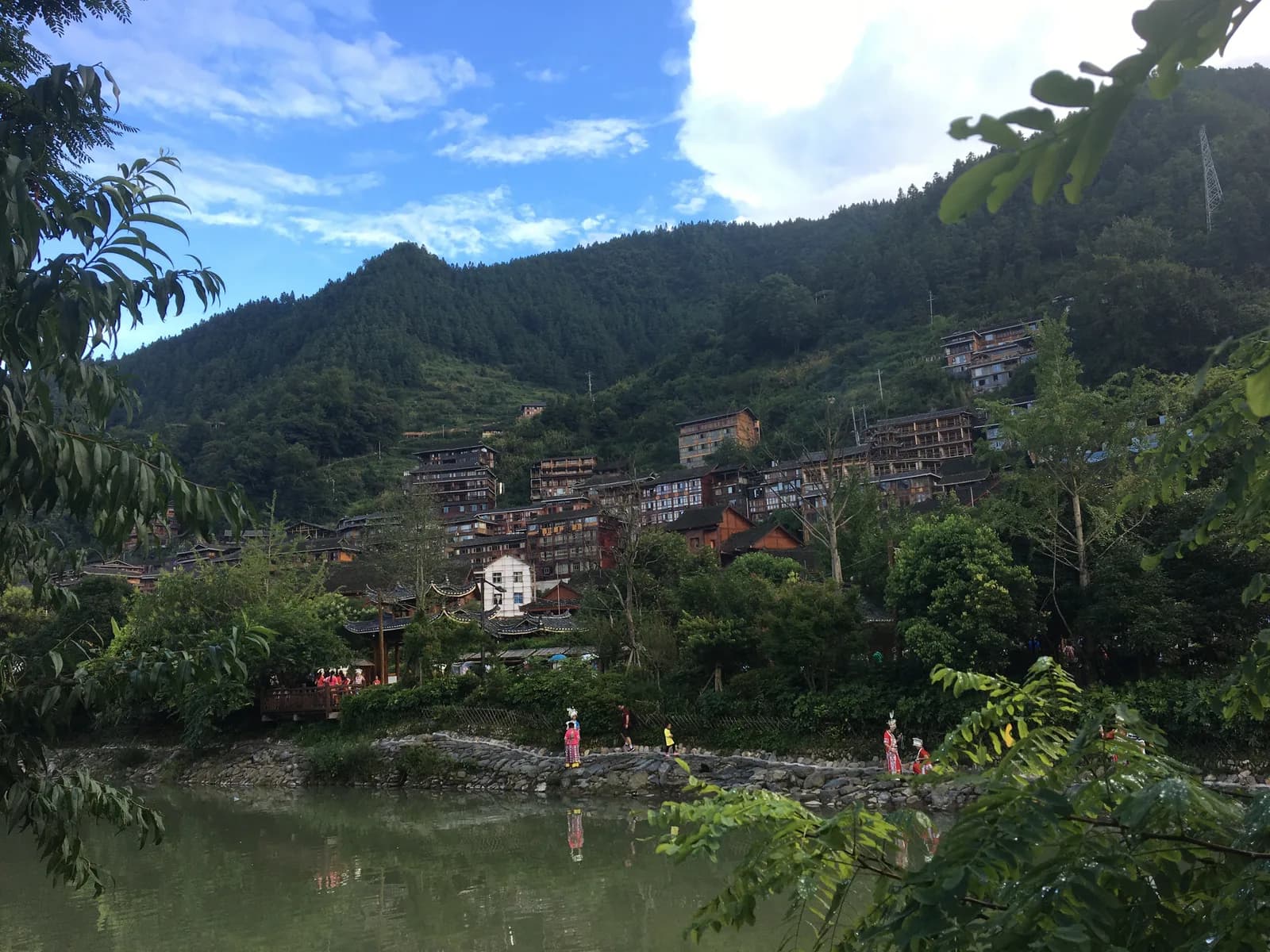 Hundreds of wooden stilt houses of Xijiang Qianhu Miao Village stacked up two green hillsides in Guizhou